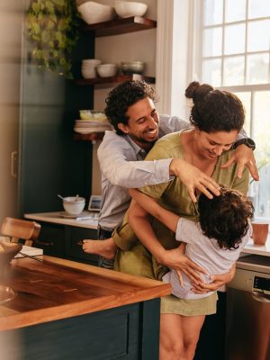 Parents playing with their son in the kitchen. Two happy parents laughing and having fun with their young son at home. Family of three spending some quality time together.