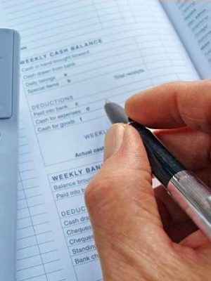 Hand with a pen over an accounts book